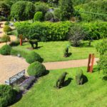 A panoramic view of Sunnyside Gardens, showcasing lush greenery, manicured bushes, and inviting pathways under a clear sky.