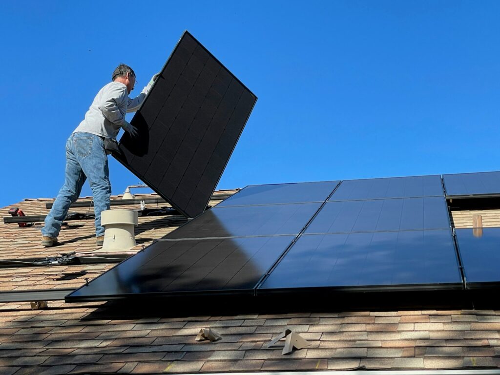 Rooftop solar panels on a modern sustainable home, absorbing sunlight with a clear blue sky in the background