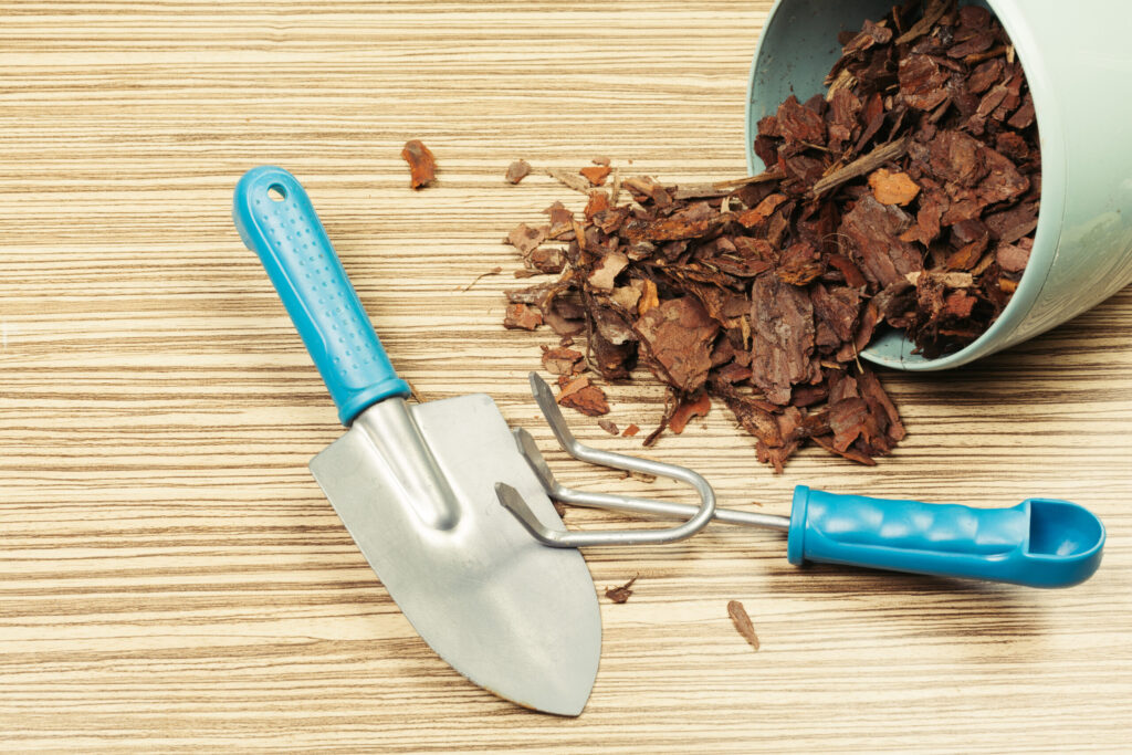 Garden tools and bucket full of organic mulch