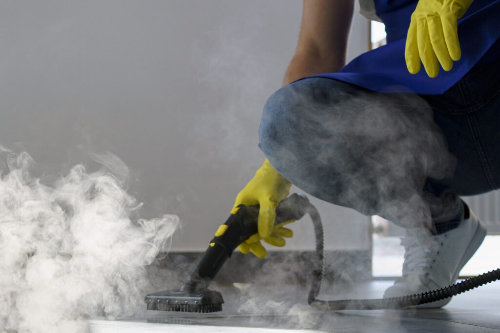 person using steam mop to clean floor.